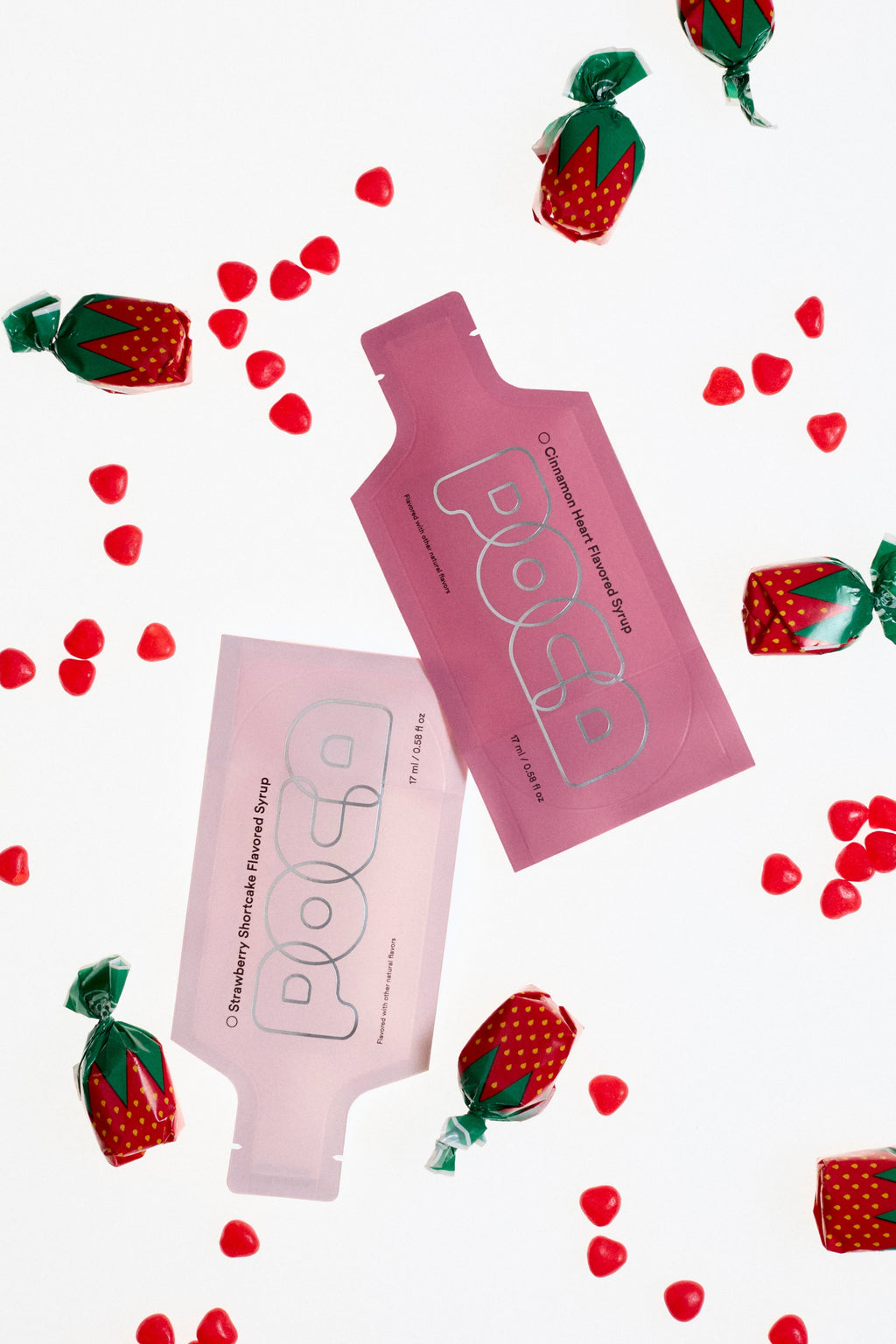 Pink POCA pouches with strawberry and cinnamon heart decorations scattered around.