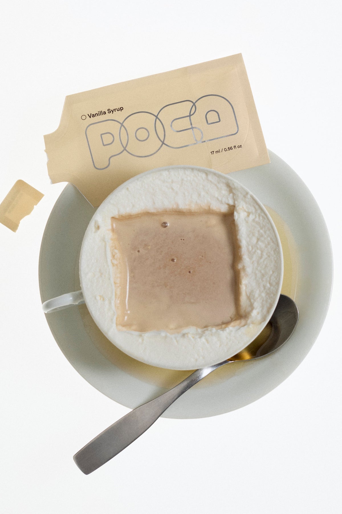 Vanilla syrup packet ripped opened and labeled 'POCA'  laying on a cappuccino.