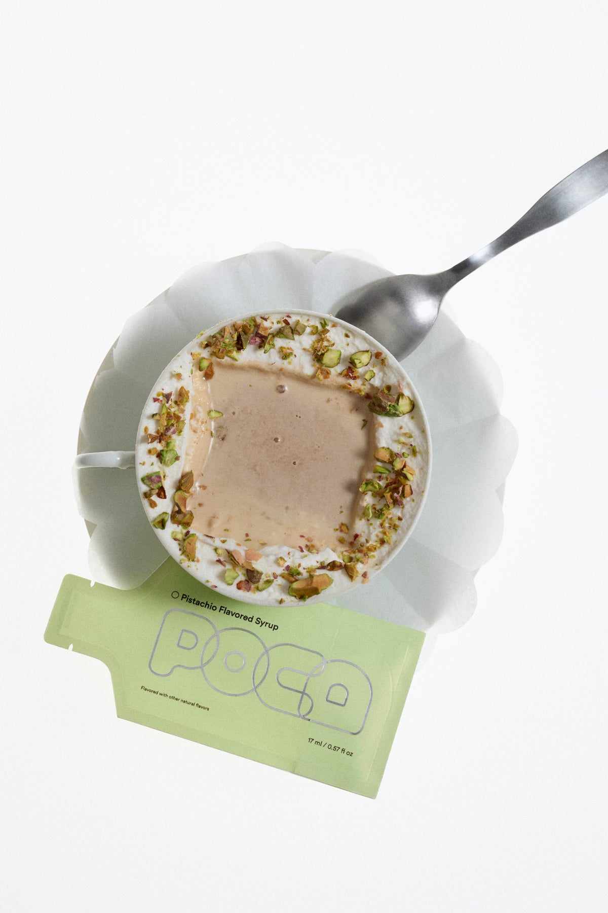 Small plate with dessert, spoon, and a green packet labeled 'POCA' on a white background.